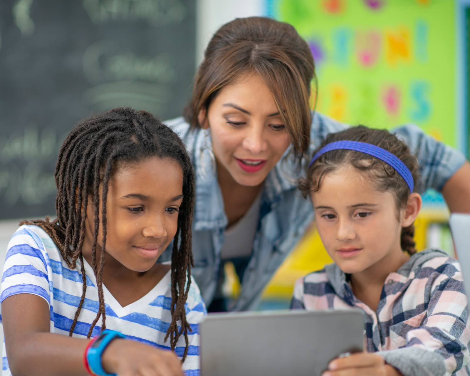 Teacher guiding students with technology in the classroom